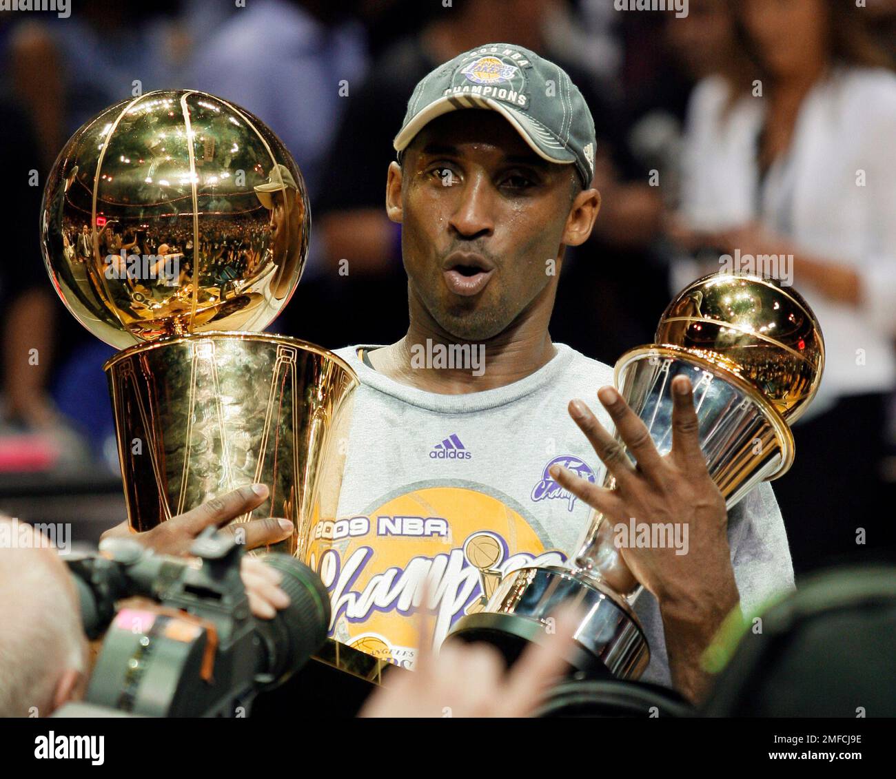 Download Kobe Bryant with a championship trophy.