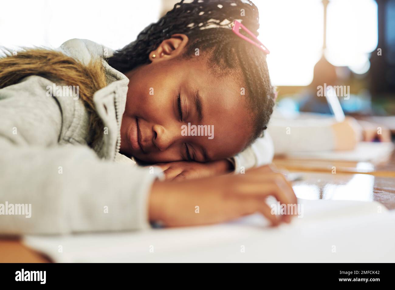 Nap time for the little wiz kid. an elementary school girl sleeping on her desk in class. Stock Photo