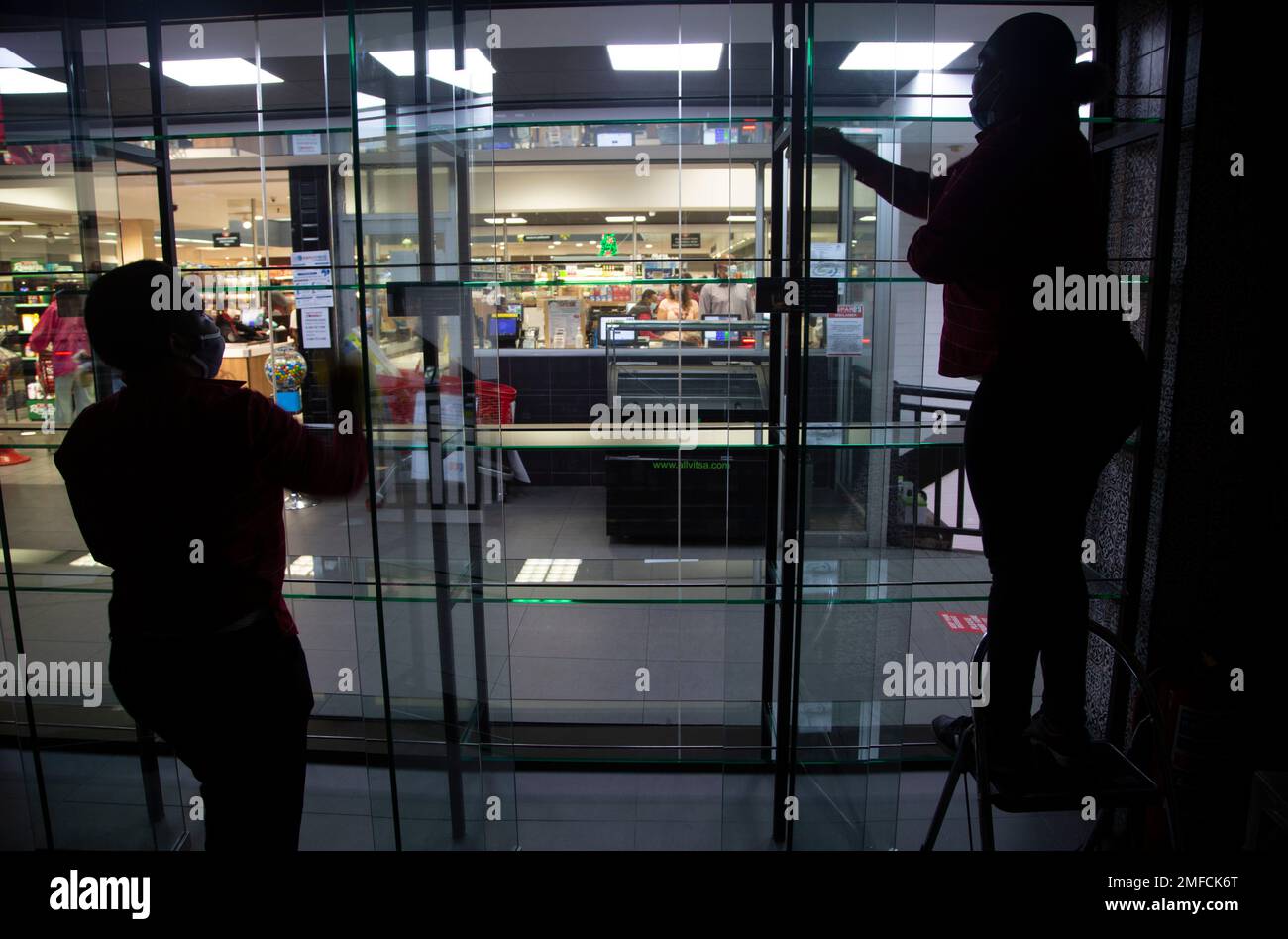 Workers clear the display shelves of a closed liquor store in