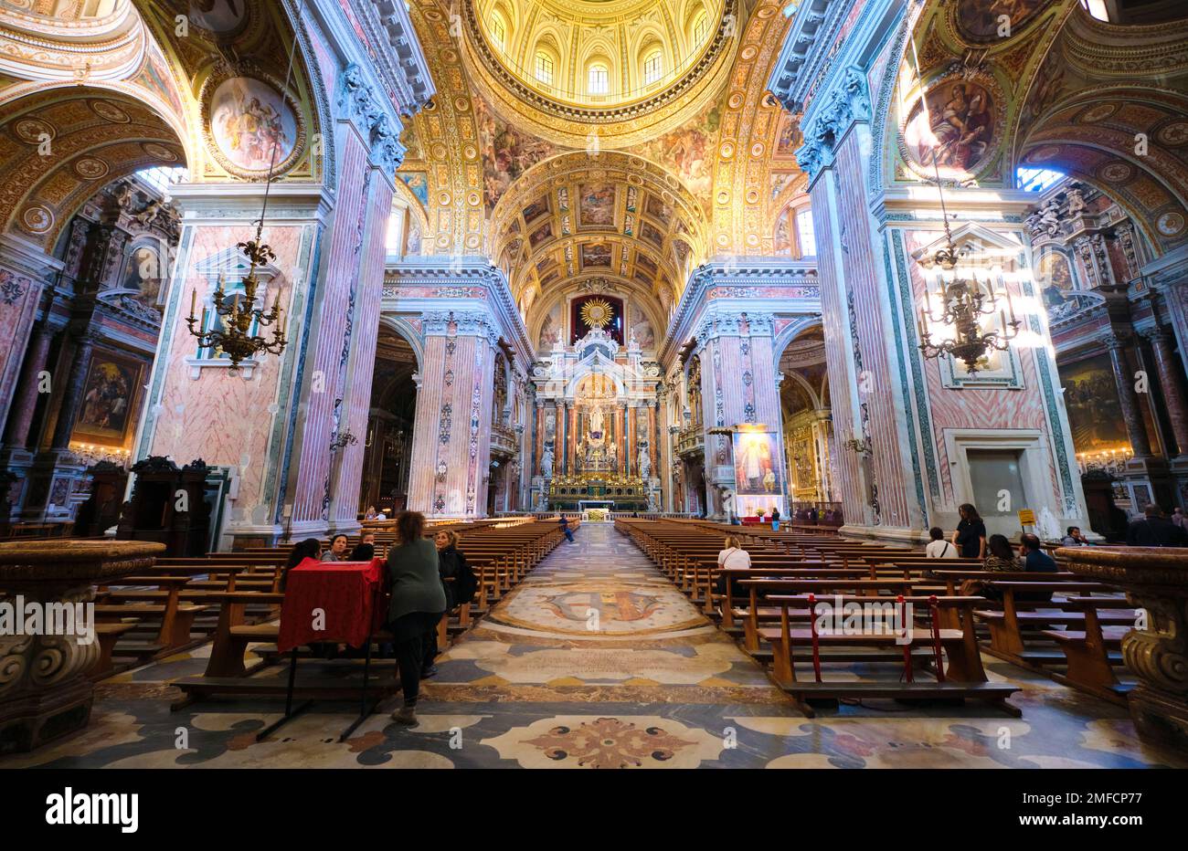 Interior view of the central nave, aisle section with soaring, gold, double vault ceiling and dome. At the Chiesa del Gesù Nuovo Catholic church in Na Stock Photo