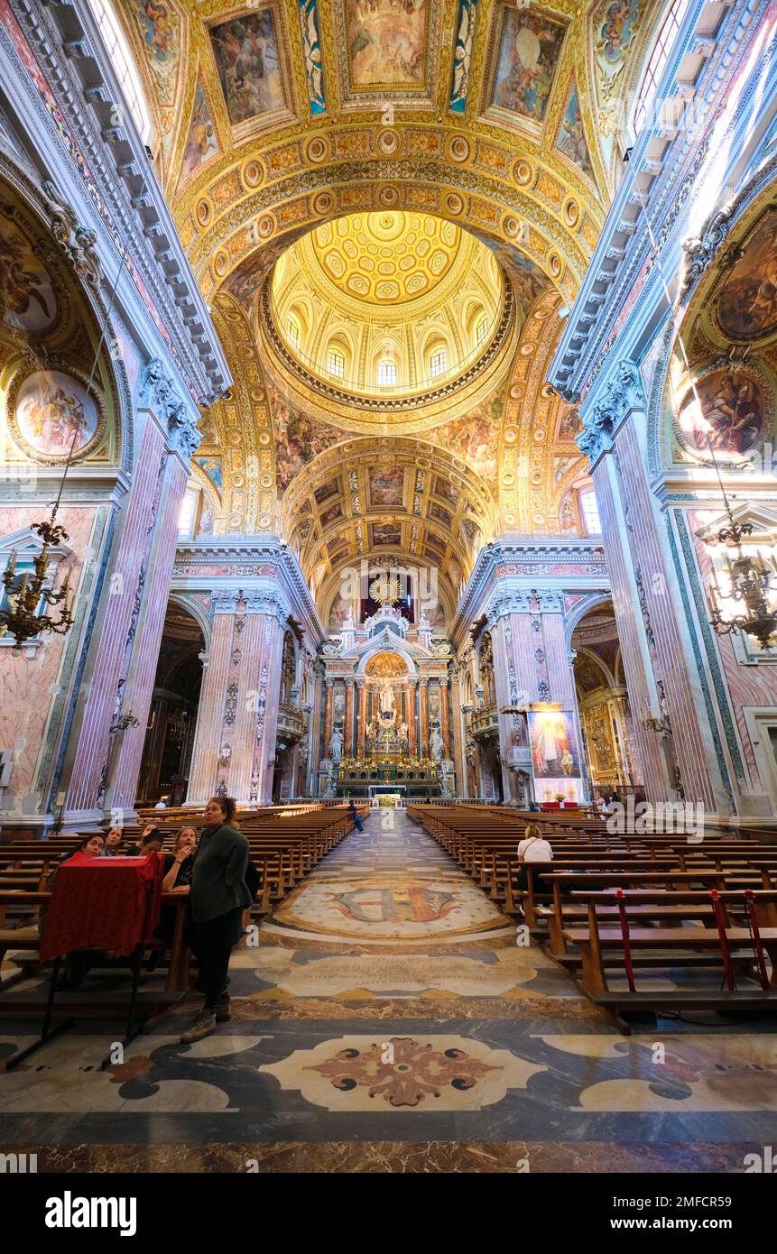 Interior view of the central nave, aisle section with soaring, gold, double vault ceiling and dome. At the Chiesa del Gesù Nuovo Catholic church in Na Stock Photo