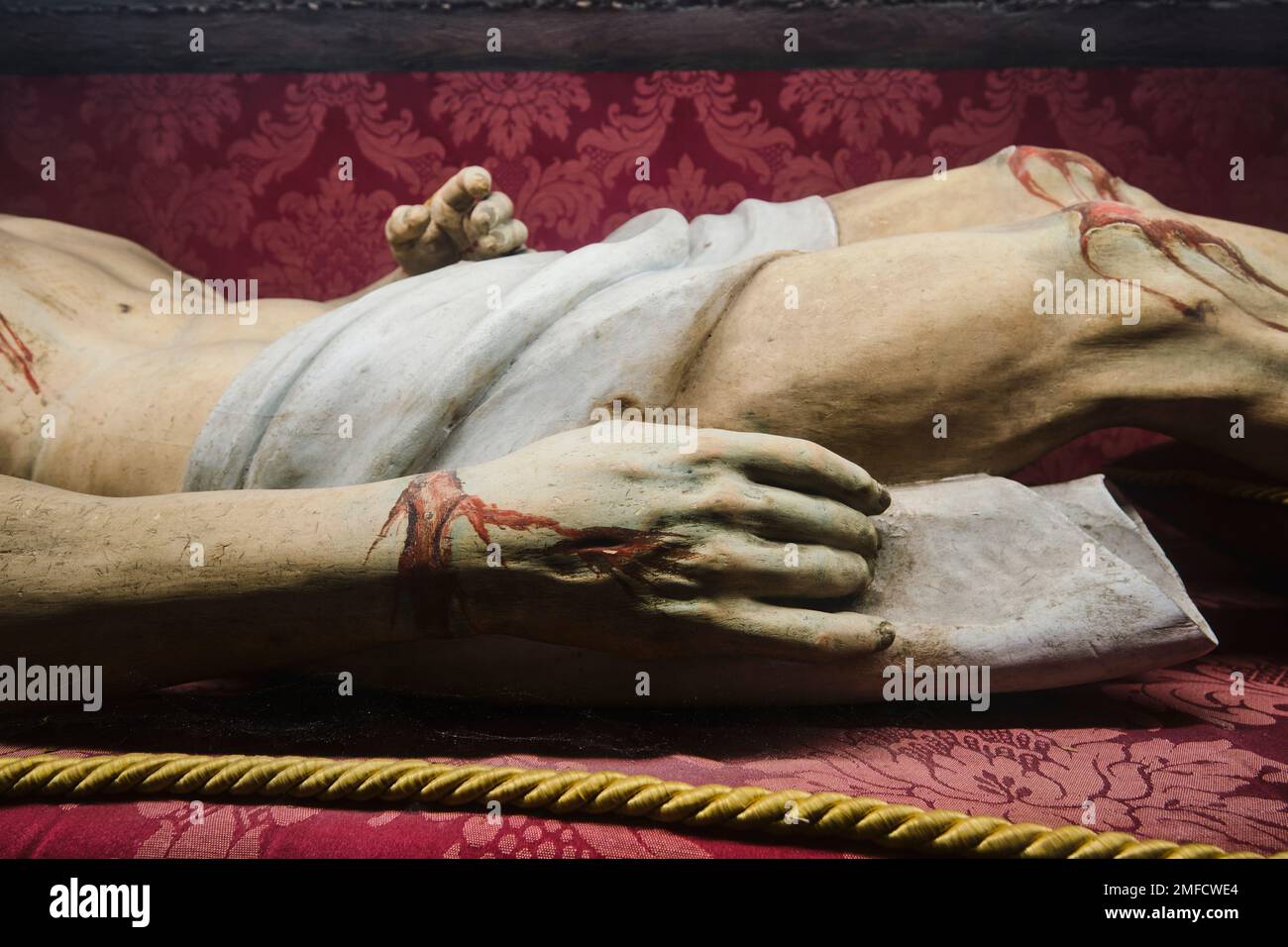 A dead Jesus Christ, lying in state in a glass case. Detail of his bloody hand and knees, from stigmata. At the Chiesa del Gesù Nuovo Catholic church Stock Photo