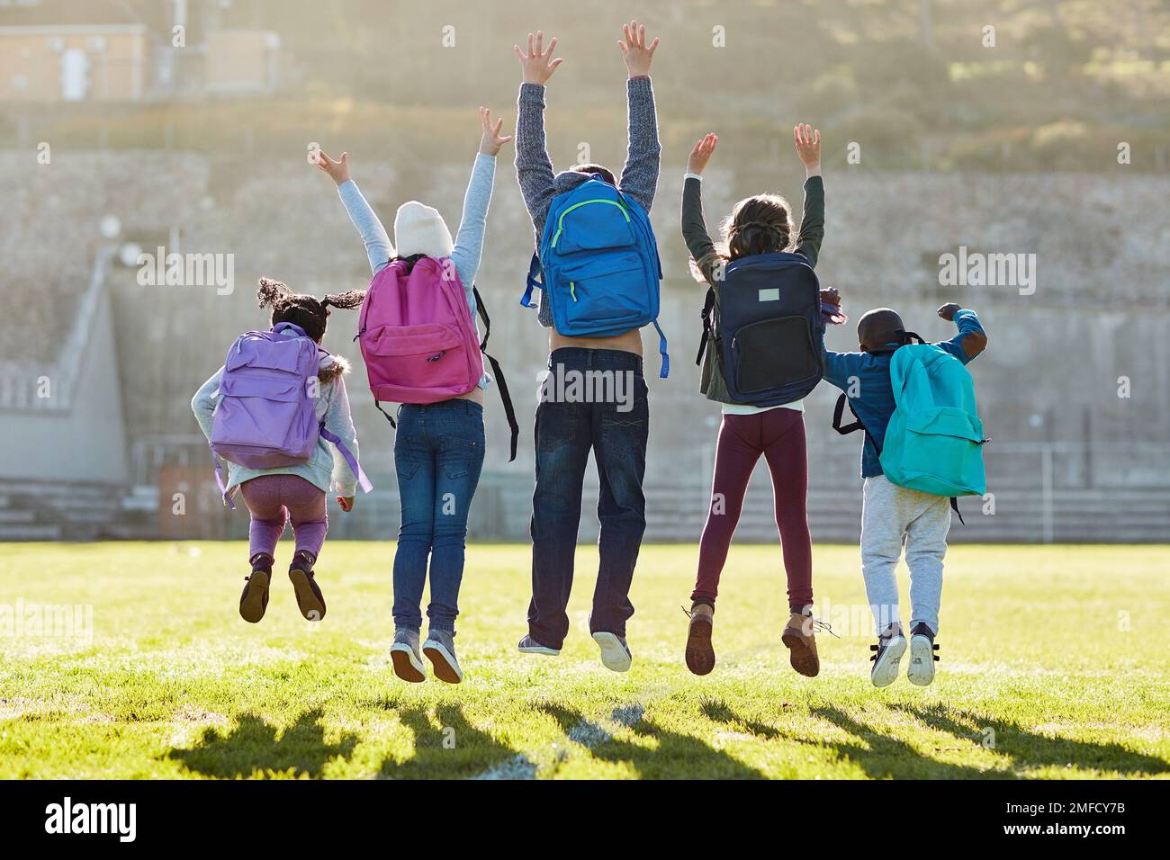 Jumping for joy. Rearview shot of elementary school kids jumping outside. Stock Photo