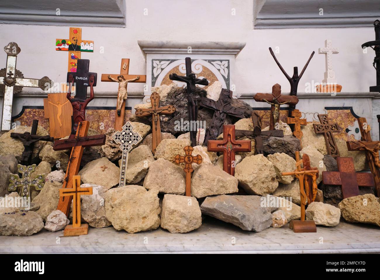 Inside the church, a small, homemade, makeshift shrine of rocks and wooden crosses on a mantle. At the Catholic church, Chiesa dei Santo Filippo e Gia Stock Photo