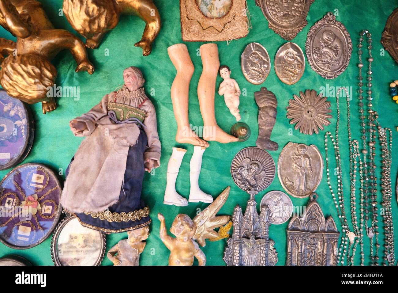 Old collectibles, Catholic relics, icons for sale at a street vendor in the Centro Historico neighborhood. Including doll legs, medallions. In Naples, Stock Photo