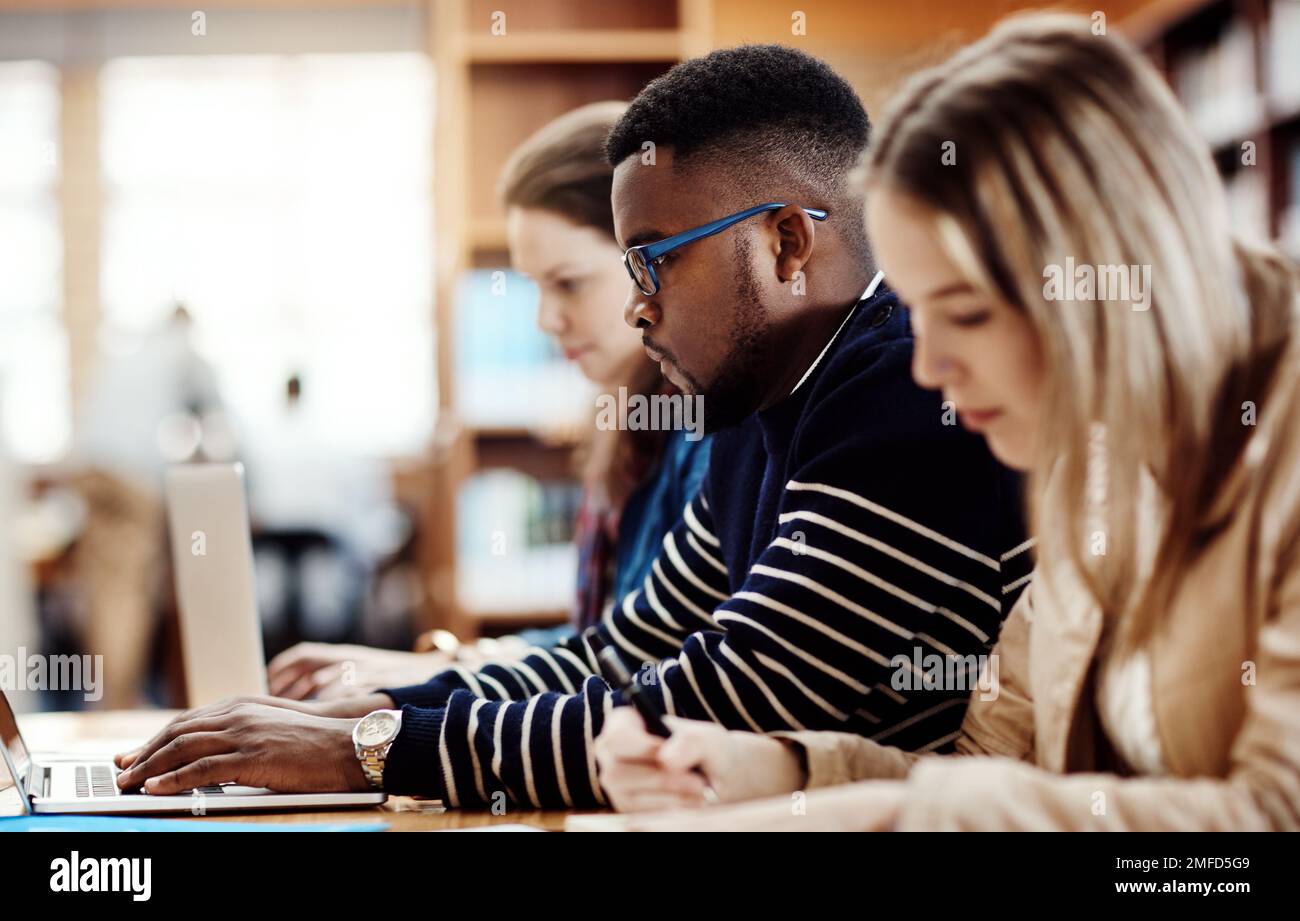 Everyone is hard at work for the test. a group of university students sitting in class at campus. Stock Photo