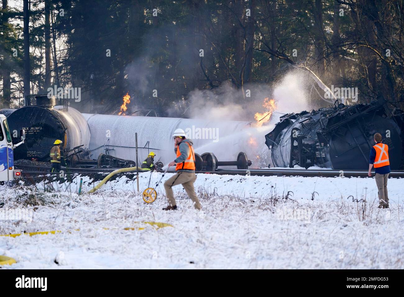 A firefighter sprays foam on a burning, derailed train car Tuesday, Dec