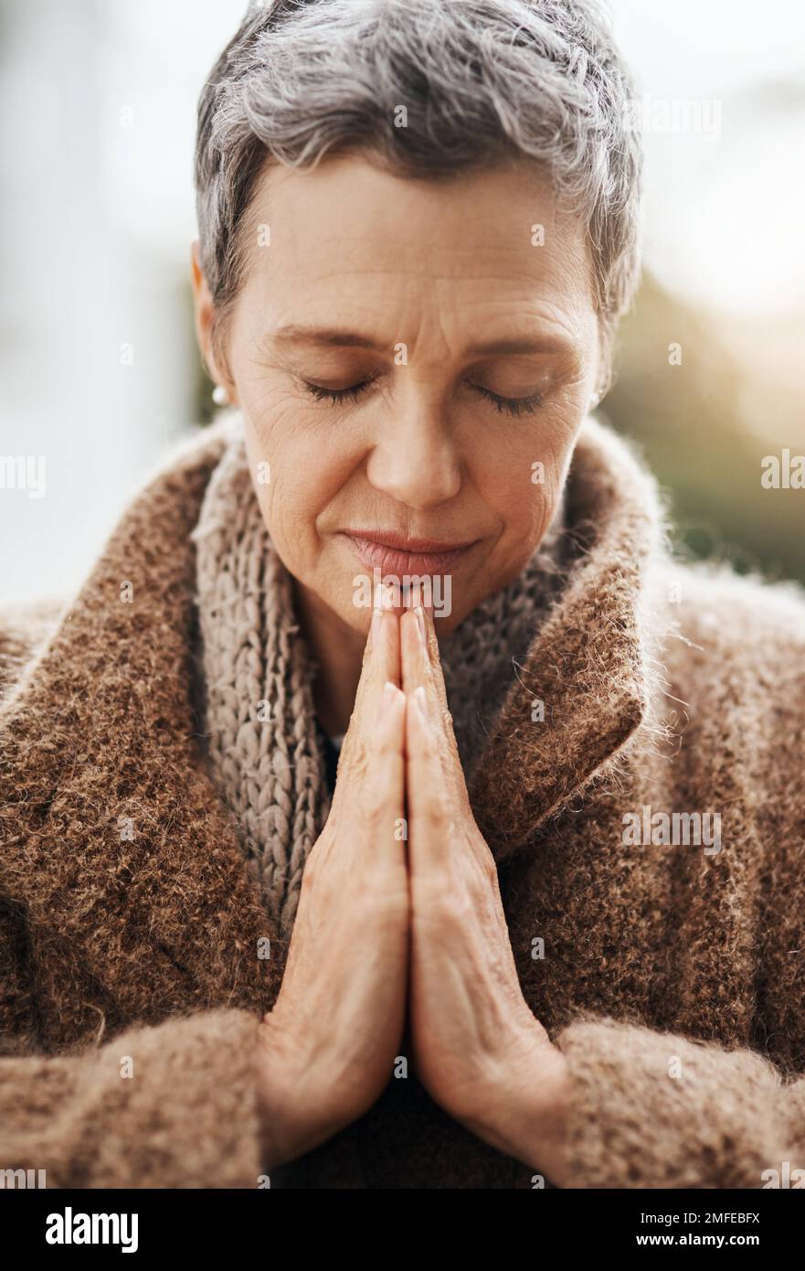 Shes hoping her prayers will get answered. a senior woman holding her hands together in prayer while sitting in her wheelchair outside. Stock Photo