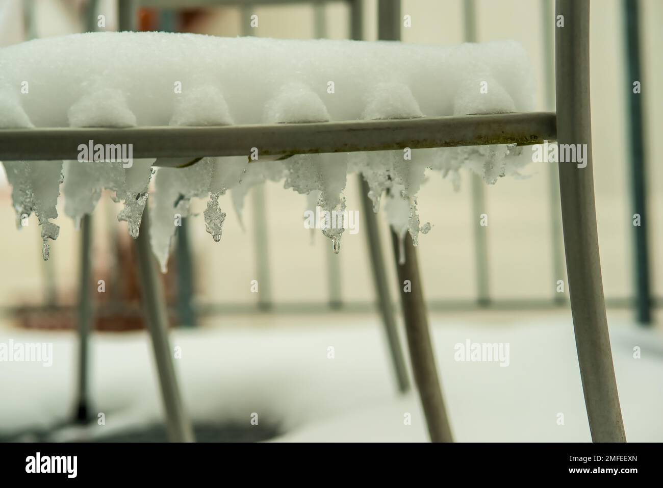 icicles and snow on a chair on a balcony Stock Photo