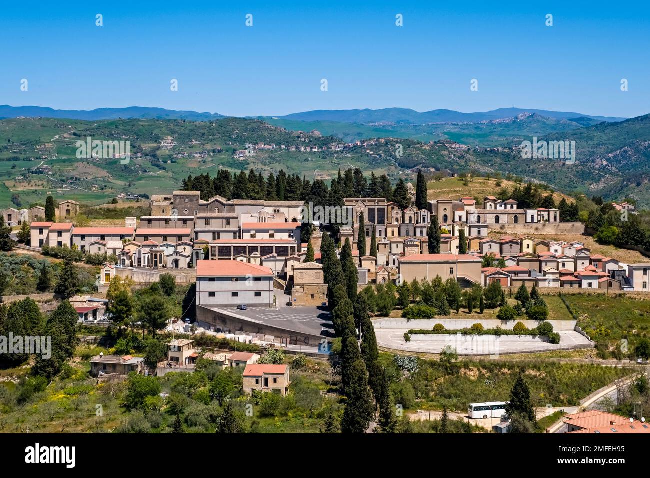 Aerial view on the cemetery of the town of Agira, agricultural landscape with green hills, trees and fields of Central Sicily in the distance. Stock Photo