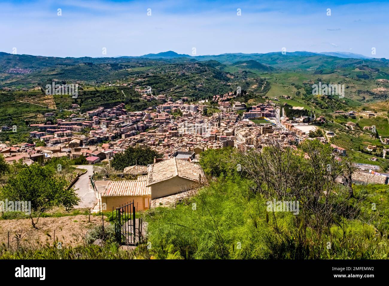 Aerial view on of the town of Agira, surrounded by agricultural landscape with green hills, trees and fields. Stock Photo
