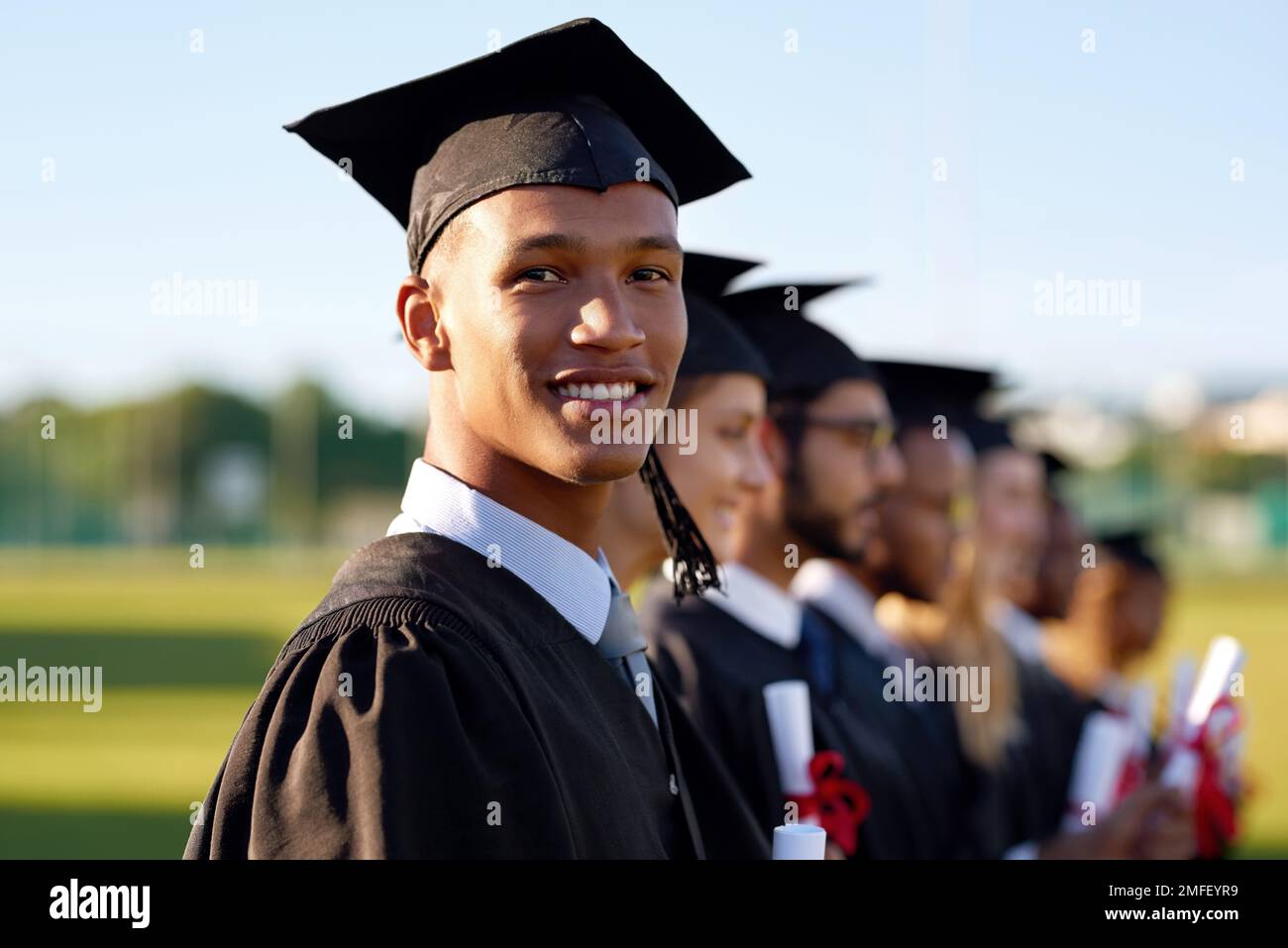 This moment will change our lives. Portrait of a university student standing in line with his classmates on graduation day. Stock Photo