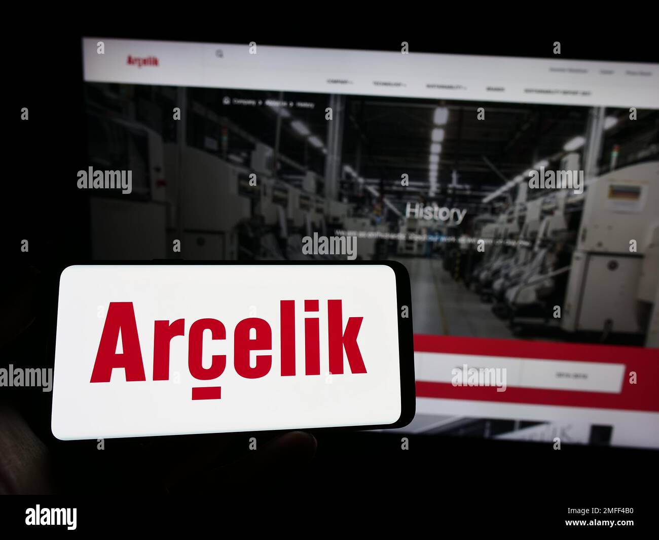Person holding mobile phone with logo of household appliances company Arcelik AS on screen in front of business web page. Focus on phone display. Stock Photo