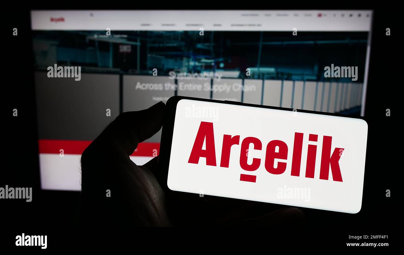 Person holding cellphone with logo of household appliances company Arcelik A.S. on screen in front of business webpage. Focus on phone display. Stock Photo