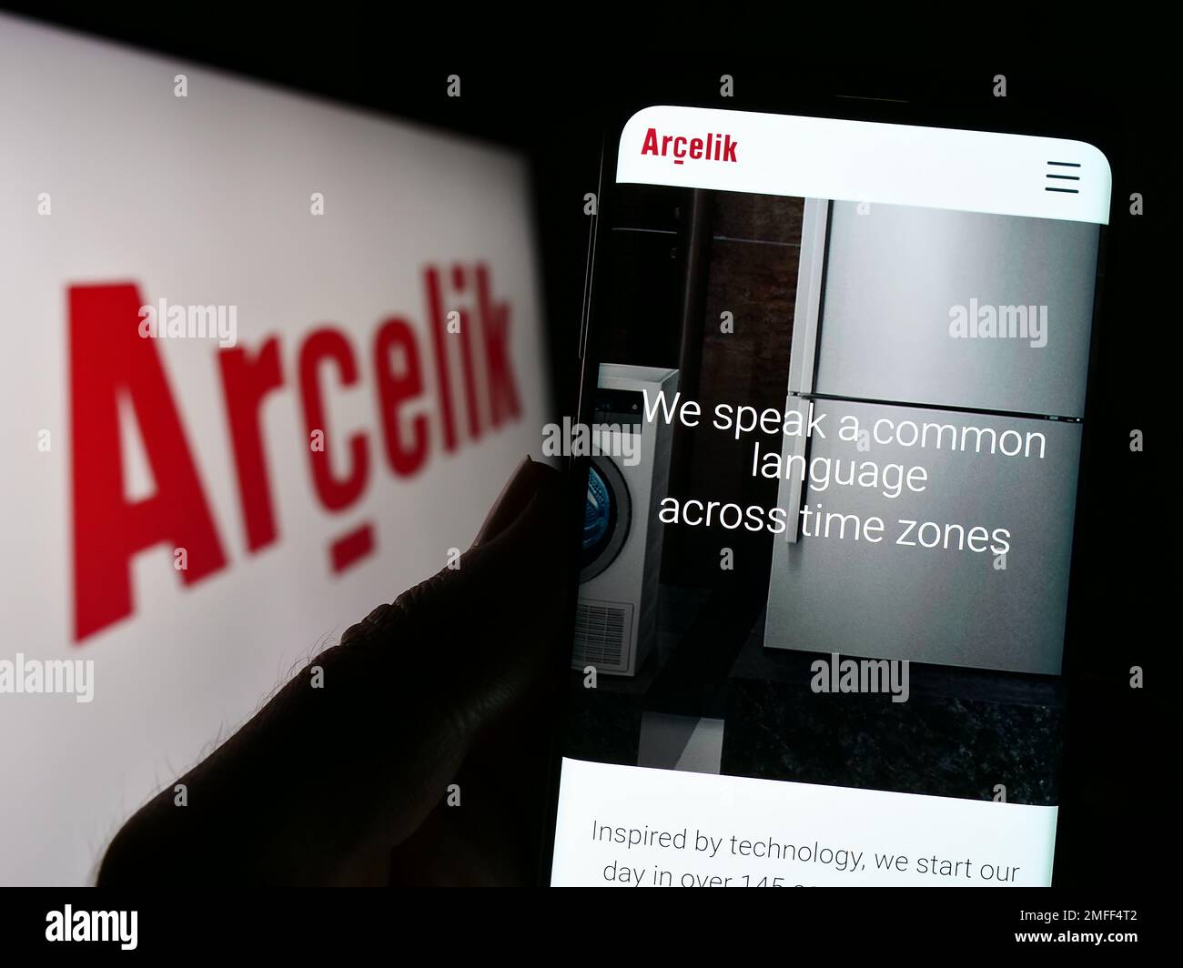 Person holding smartphone with webpage of household appliances company Arcelik A.S. on screen in front of logo. Focus on center of phone display. Stock Photo