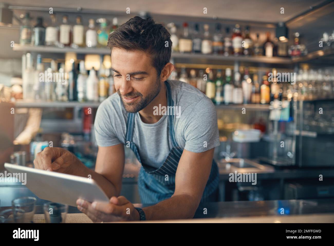The modern baristas smart assistant. a young man using a digital tablet