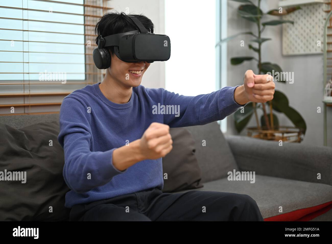 Cheery Asian man in VR headset holding imaginary steering wheel of