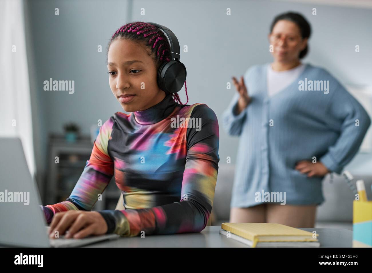 Teenage son listening music in headphones or playing online games ignoring  his mother Stock Photo - Alamy