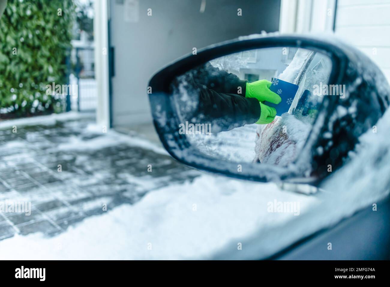 Teenager  cleans car after a snowfall, removing snow and scraping ice Stock Photo