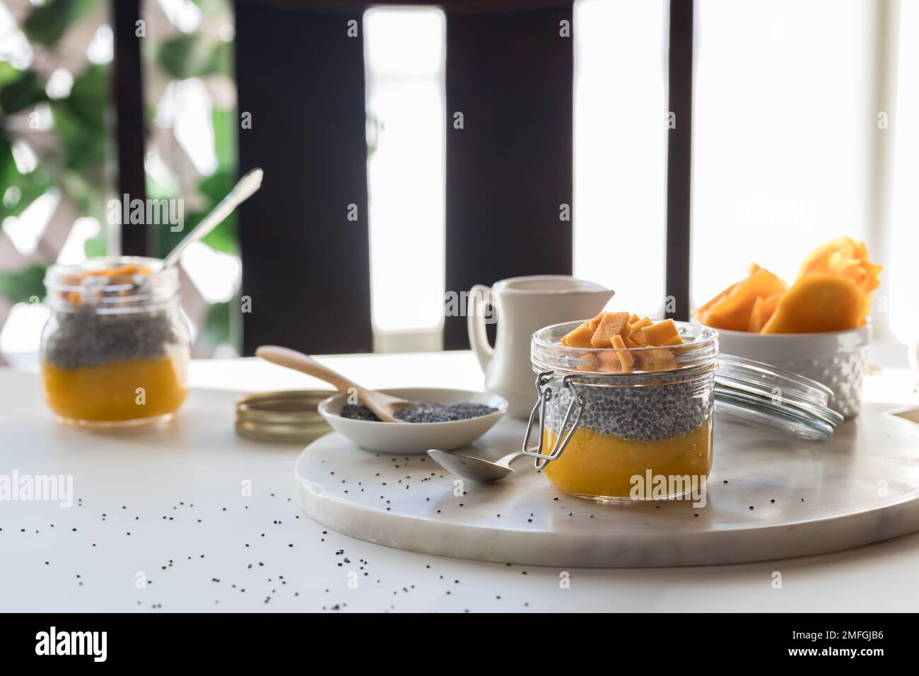 Homemade chia pudding snacks on a table with light streaming in from behind. Stock Photo