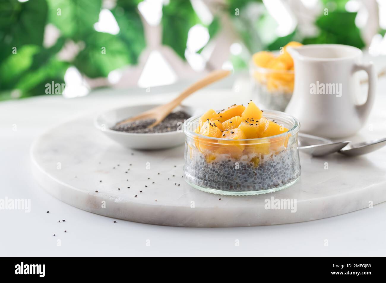 Chia pudding topped with chopped mango pieces against a blurred background. Stock Photo