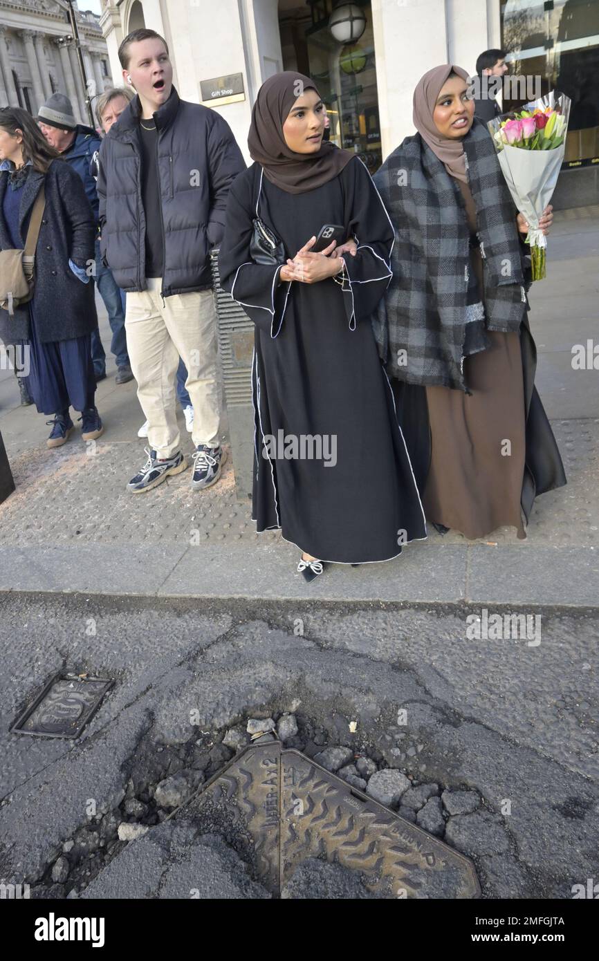 London, England, UK. People waiting to cross the road in Parliament Square - road in a poor state of repair Stock Photo
