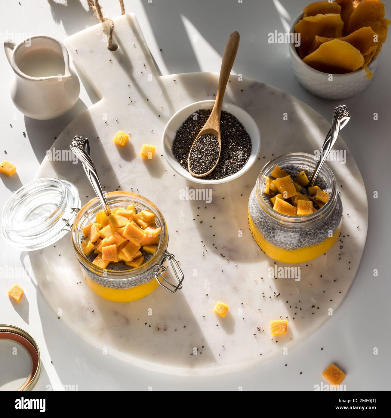 Homemade mango chia pudding parfaits on a marble slab in bright sunlight. Stock Photo