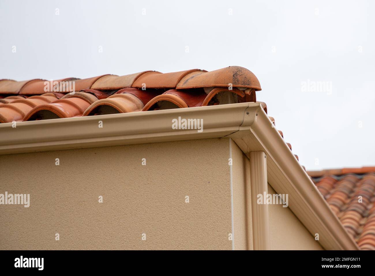 House corner with beige sand metal siding and roof with steel gutter