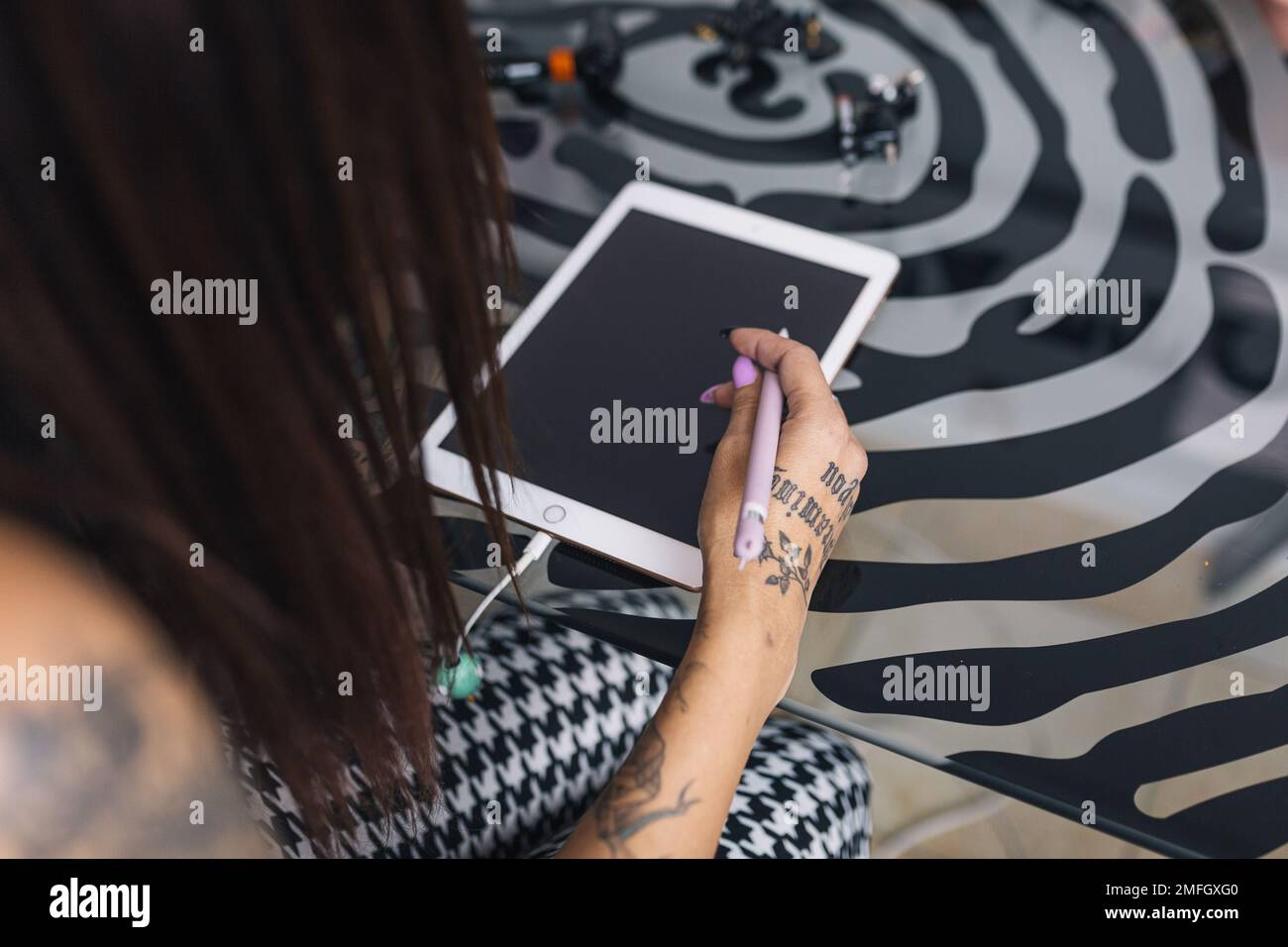 Tattoo artist hands designing a tattoo on her tablet. Stock Photo