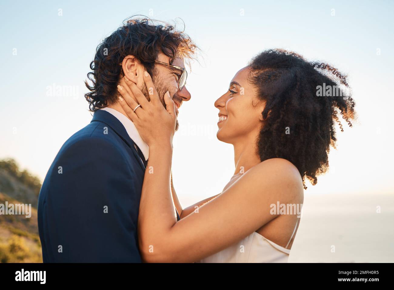 Wedding, love and interracial couple on mountain for marriage ceremony, commitment and celebration by sea. Romantic holiday, happy and bride and groom Stock Photo