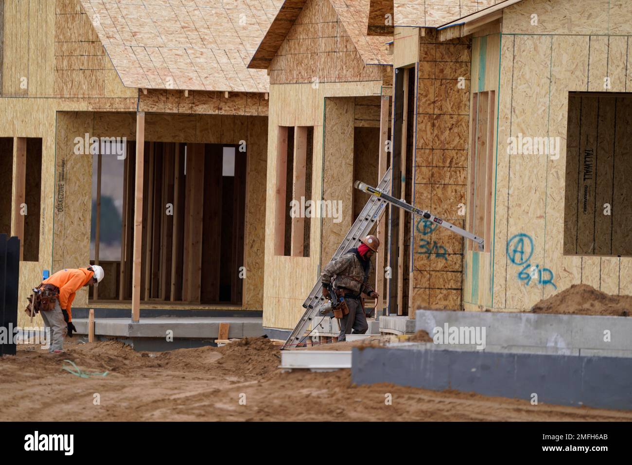 Workers toil on new homes under construction in a development near