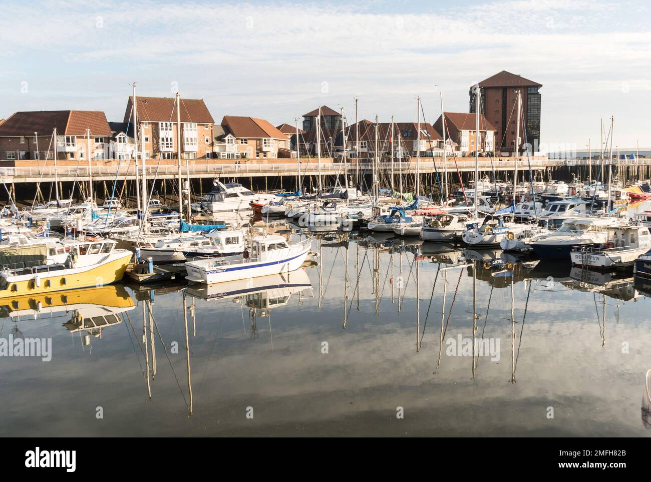 Boats and masts reflected in smooth water at Roker marina, in