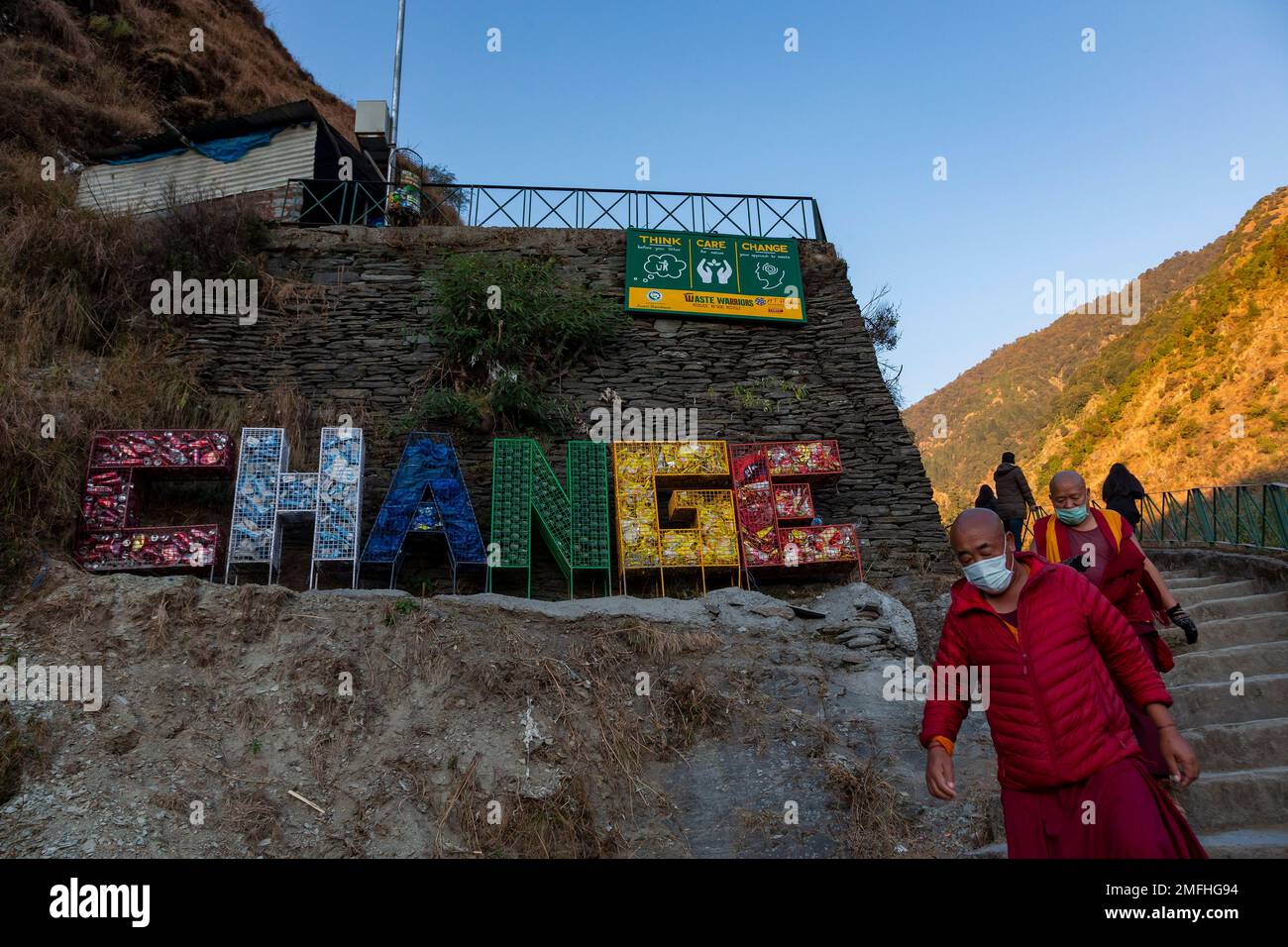 Exile Tibetan Buddhist monks wearing masks walk past an installation