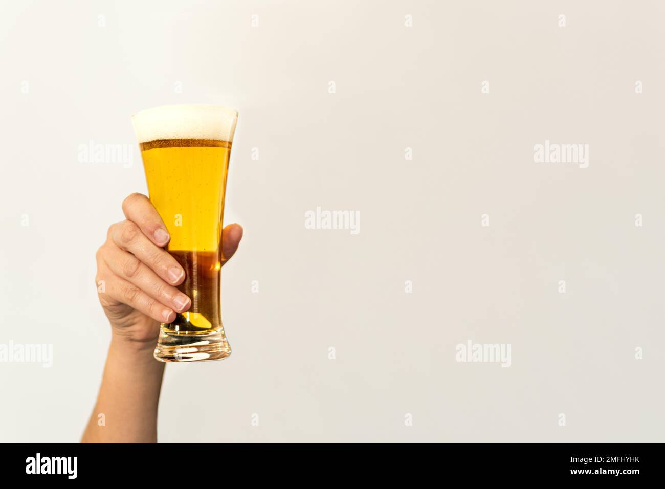 woman's raised arm holding a glass of beer with copy space next to it Stock Photo