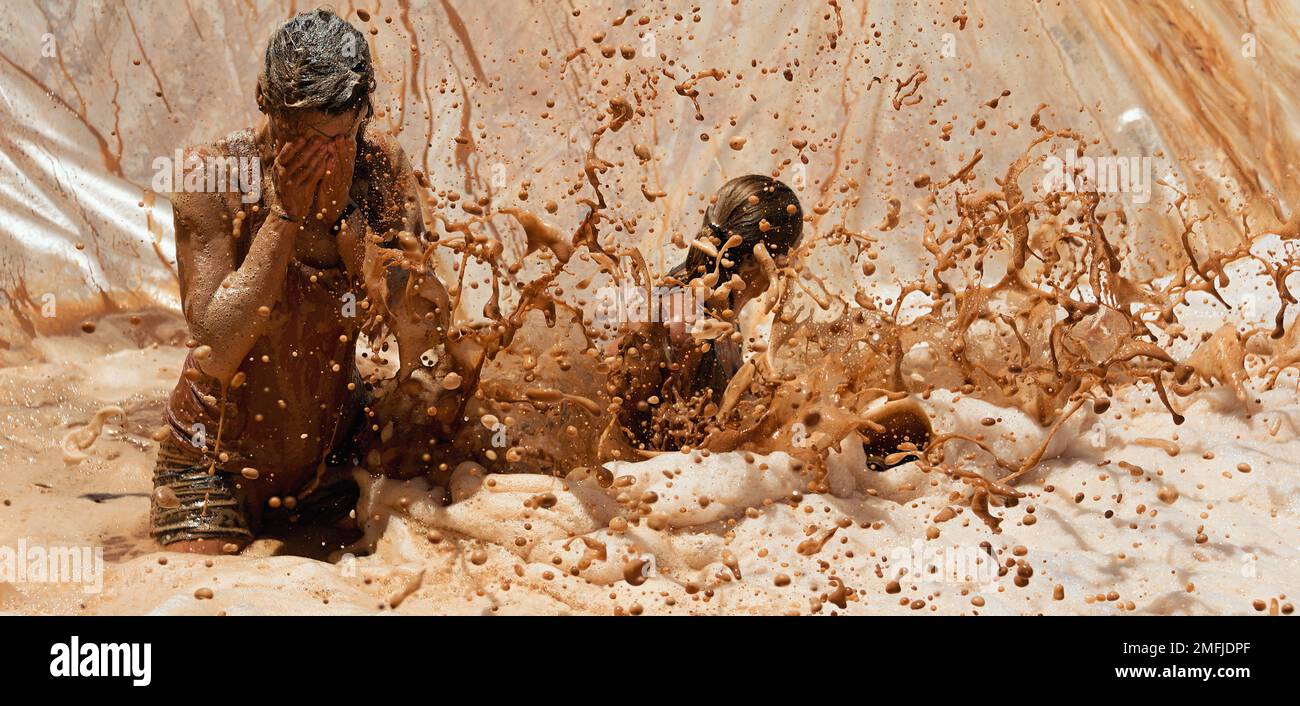 Mud race runners, jump into dirty water with foam Stock Photo