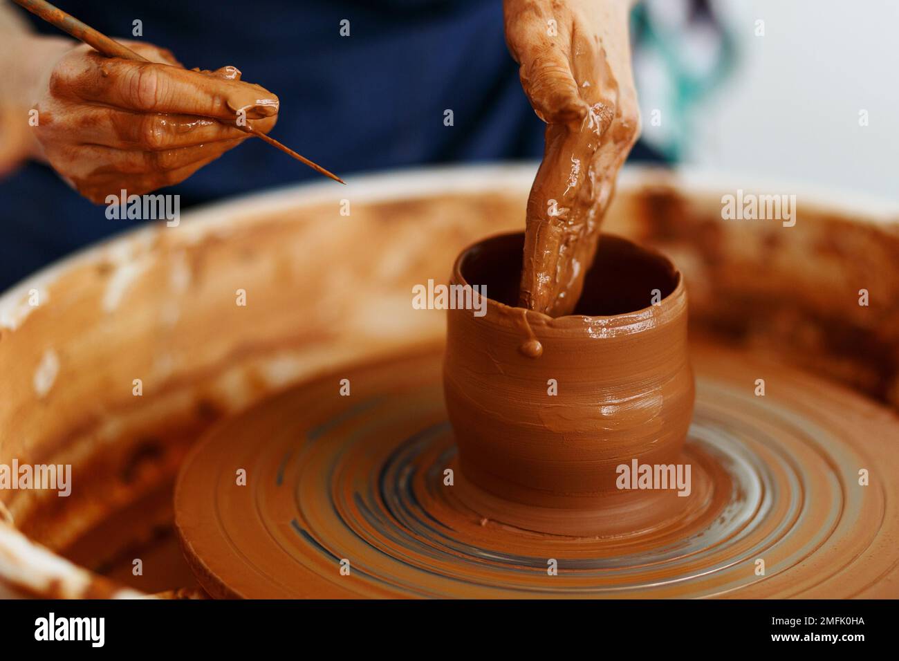 Cropped Image of hands working with Pottery Wheel, close up of shaping clay edges. Stock Photo