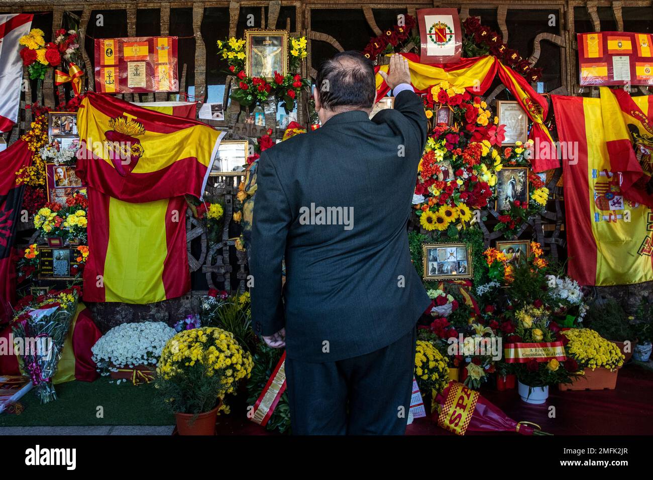 A man makes the fascist salute in front of a shrine with flowers and