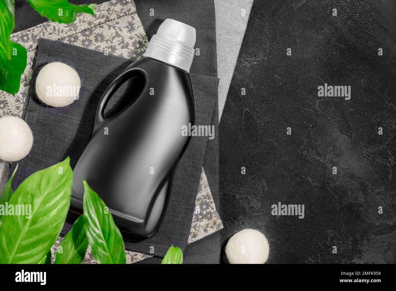 Natural laundry detergent mockup for washing black clothes. Washing detergent concept with bottle of washing gel or fabric softener on textile napkins Stock Photo