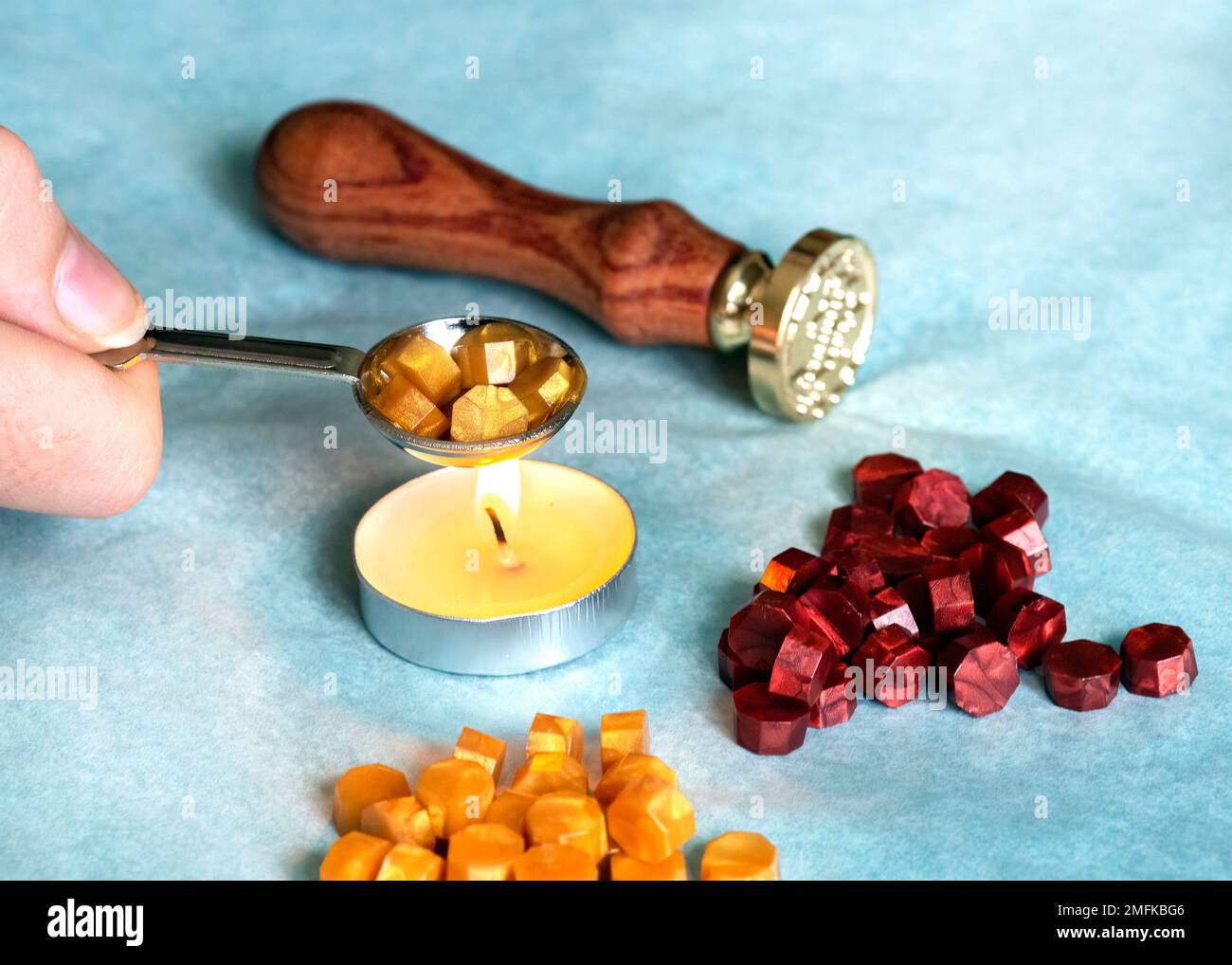 hand holding a candle wax melting spoon and seal a traditional using