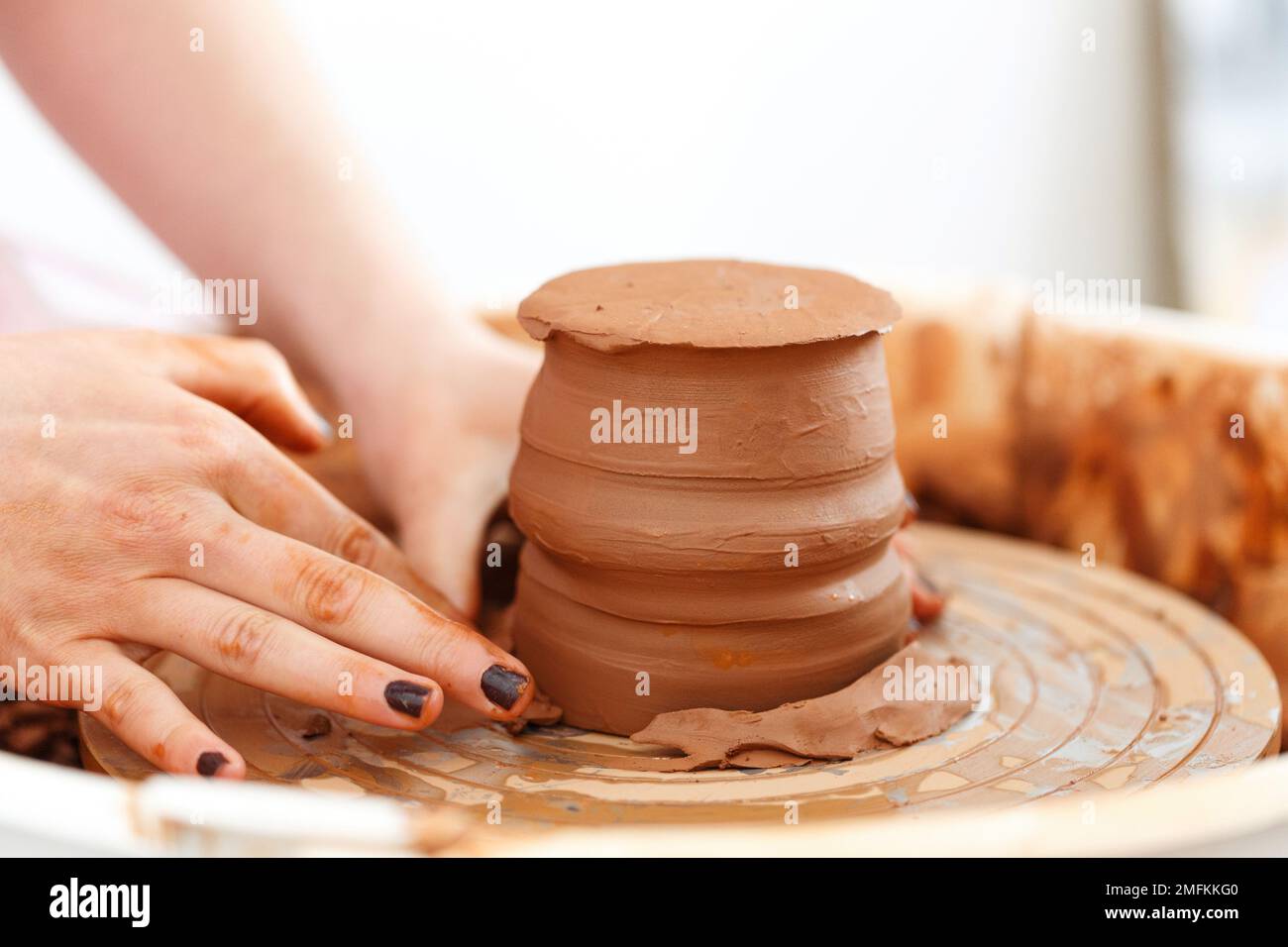 Cropped close up image. Woman's hands molding clay, making a clay pottery in the handicraft workshop. Artisan production earthenware concept. Macro sh Stock Photo