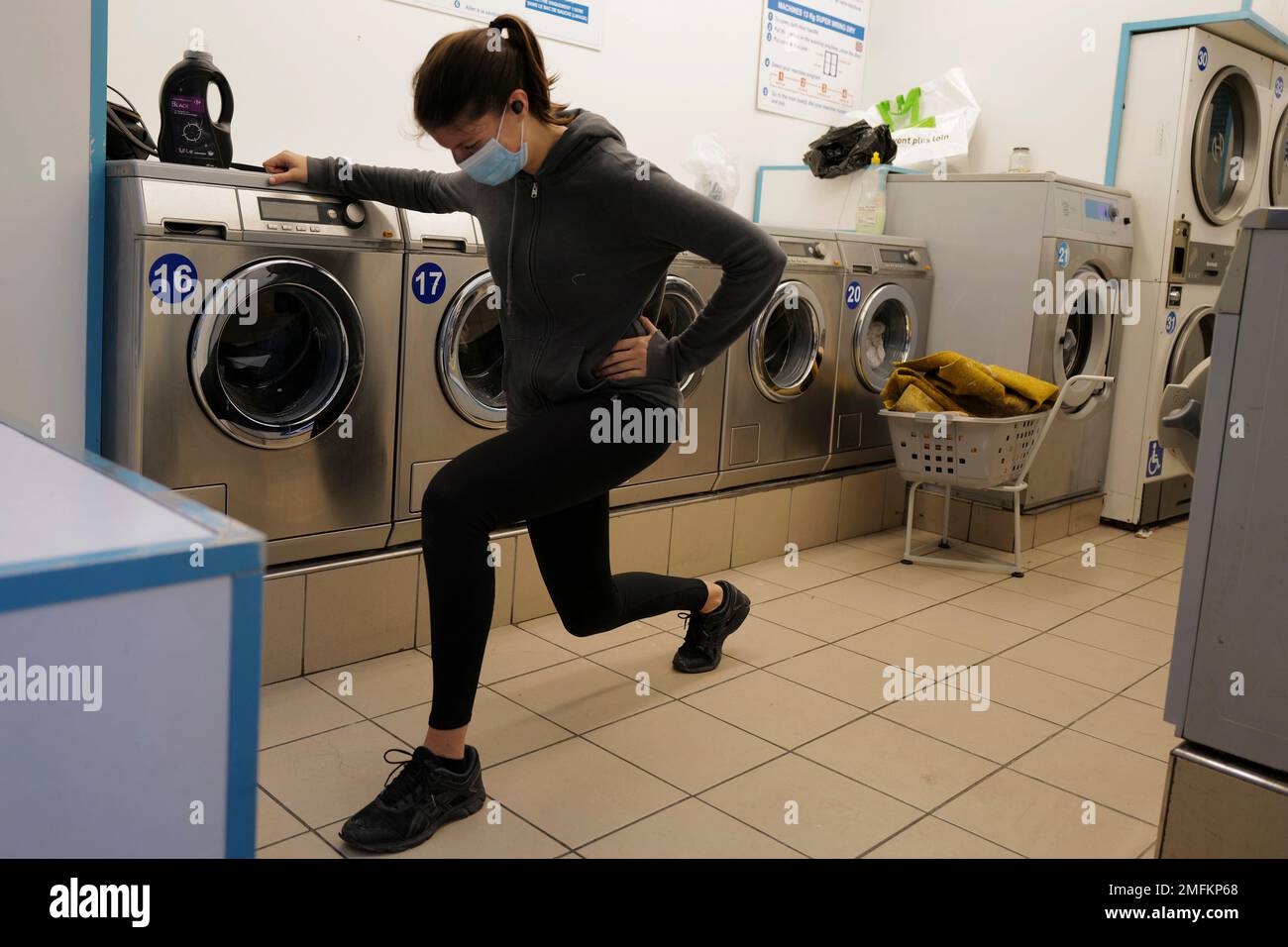 Manon, stretches while waiting for her clothes drying, in a laundromat