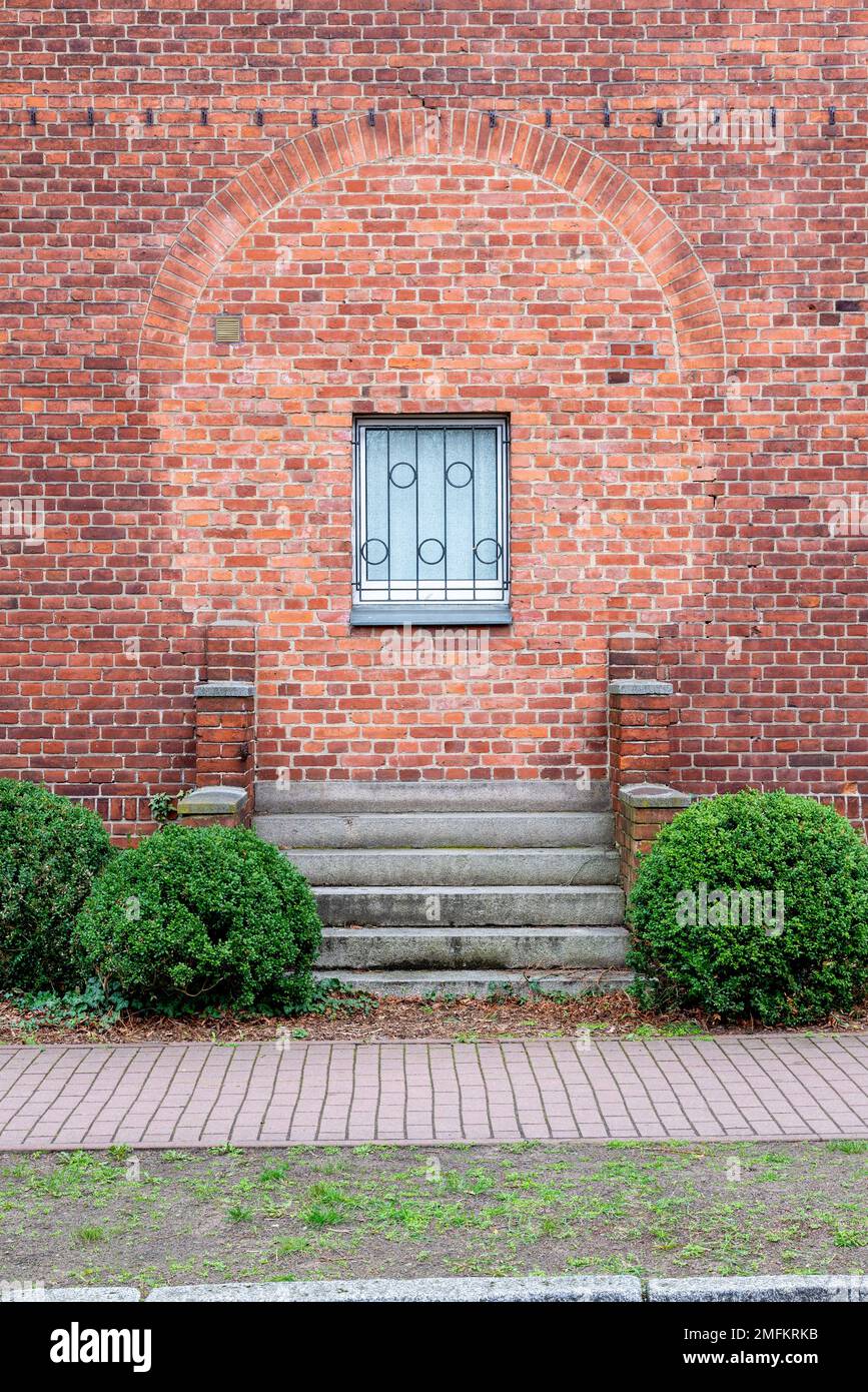 A red brick wall with a window, where before a door was bricked up. The ...
