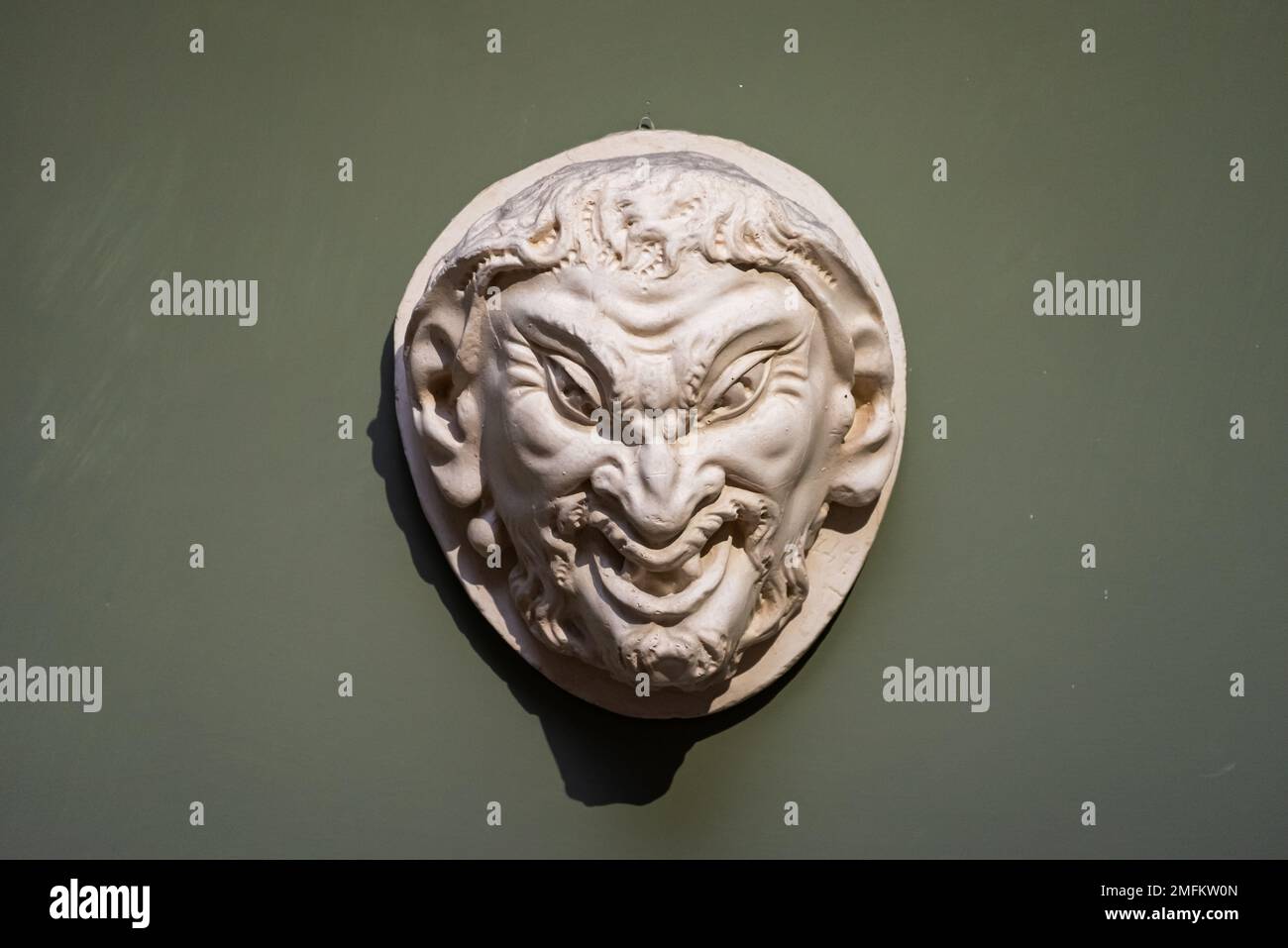 Ugly face of evil man carved in a stone amulet Stock Photo