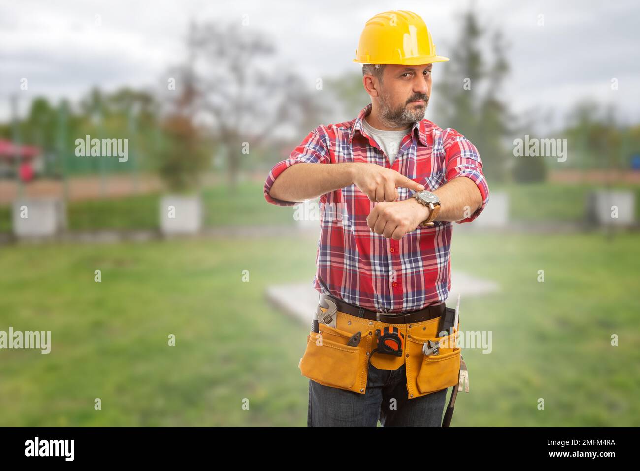 Angry worker pointing at his wristwatch as being late to workplace concept Stock Photo