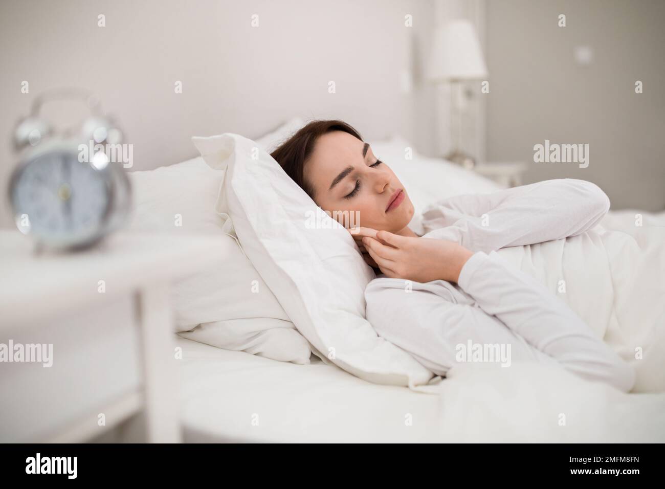 Pretty woman in white pajamas sleeping in bed at bedroom Stock Photo