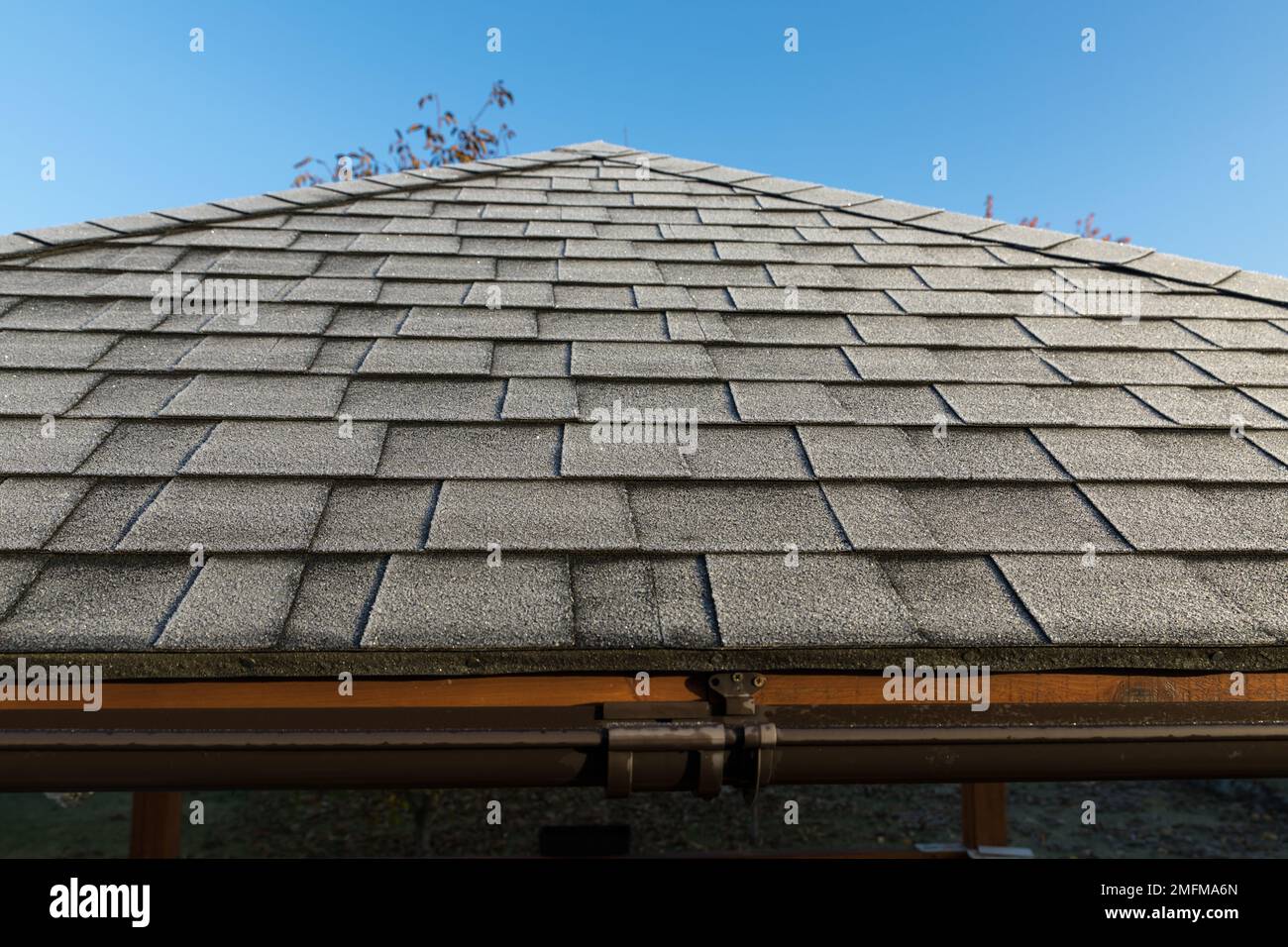 Frosted roof covered with bitumen shingles. The beginning of winter