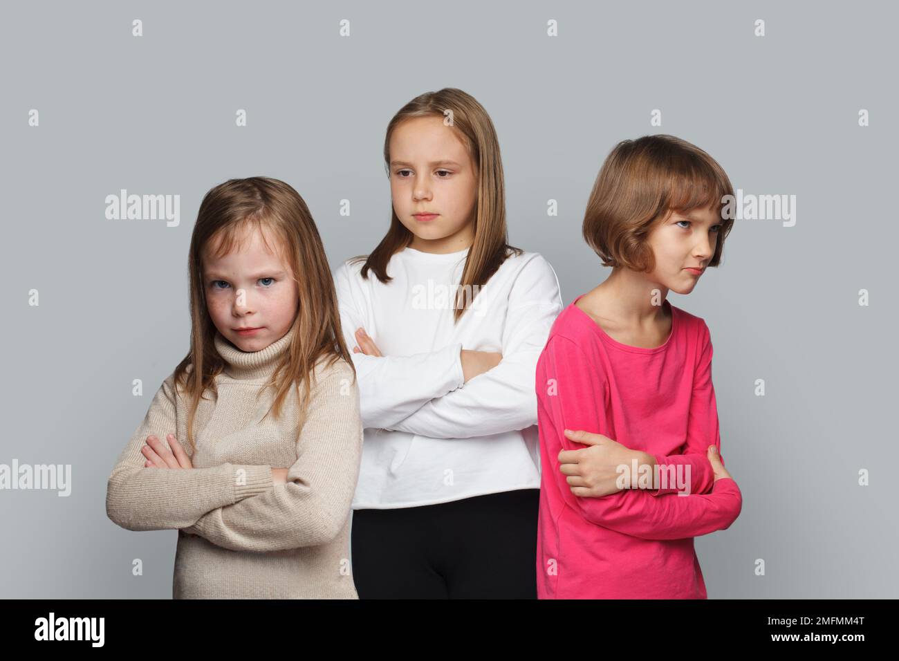 Three upset kids friends standing with crossed arms. Young girls 8-10 years old Stock Photo