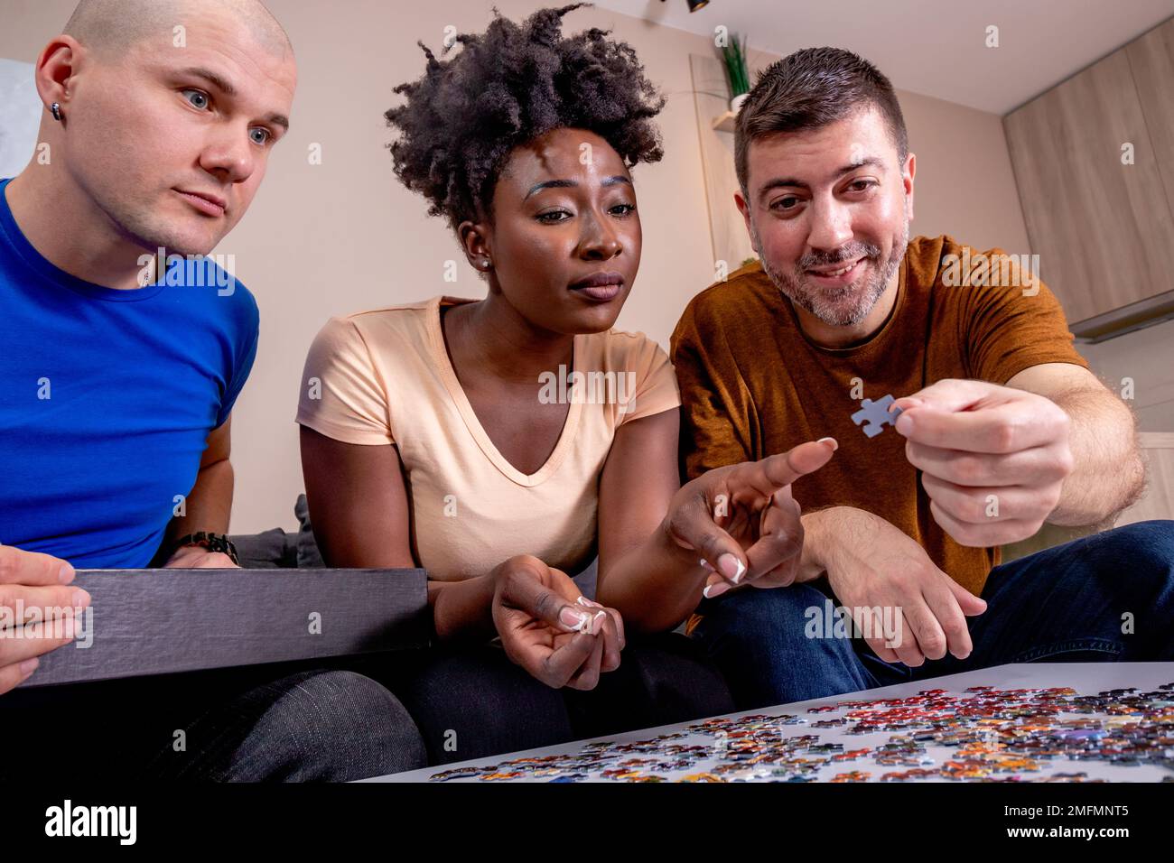 Friends playing jigsaw puzzles at home. Solving problems and putting ...