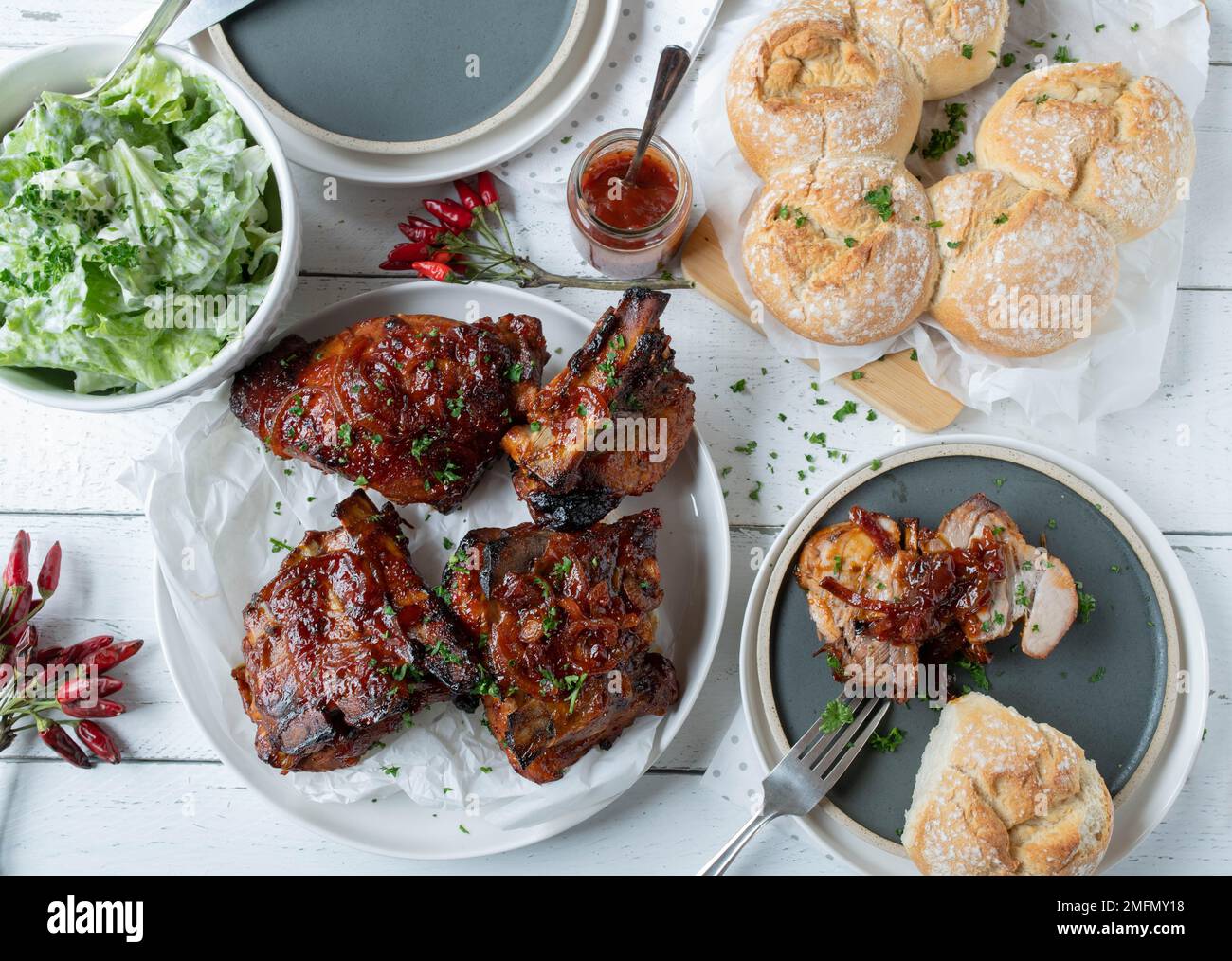 Thick pork ribs with homemade barbecue sauce, salad and bread wreath. Delicious barbecue meal Stock Photo