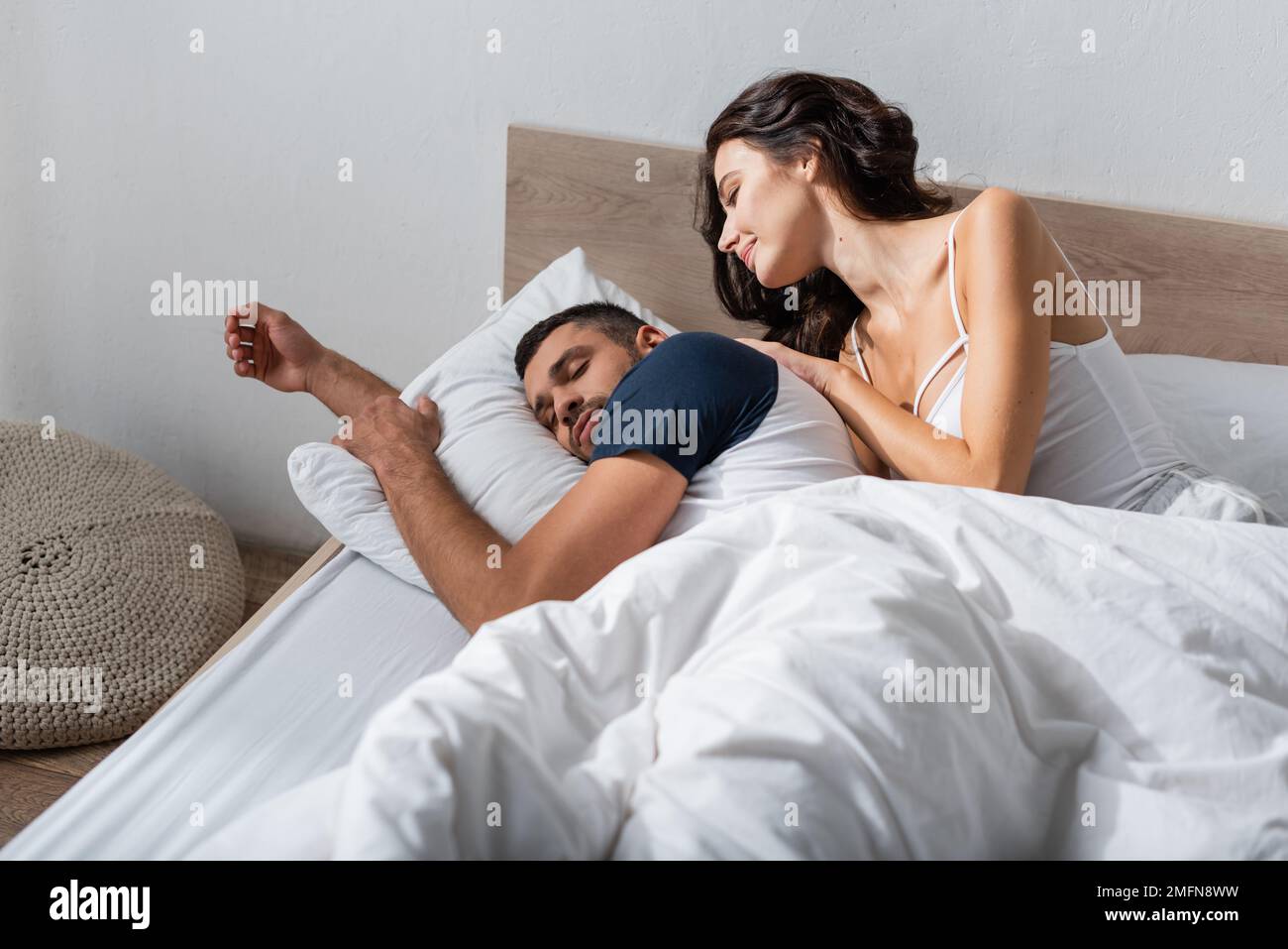Brunette woman looking at bearded boyfriend sleeping on bed,stock image Stock Photo